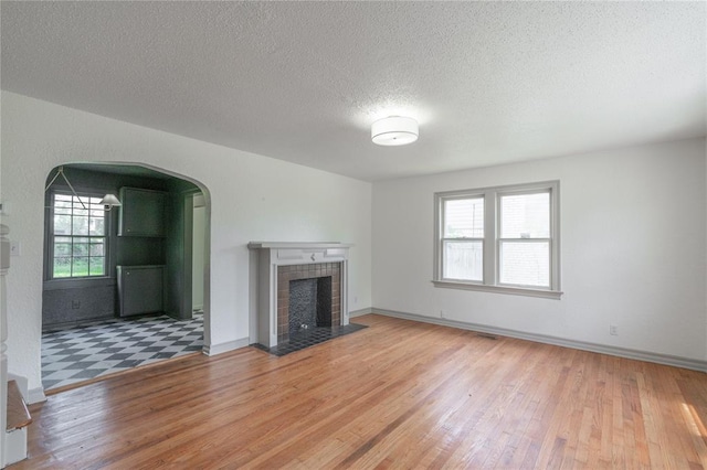3125 NW 24th St, Oklahoma City, OK 73107 - unfurnished living room with healthy amount of natural light, wood finished floors, arched walkways, and a textured ceiling