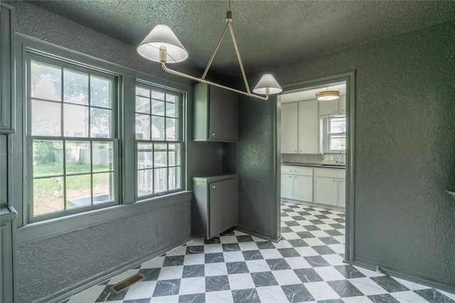 3125 NW 24th St, Oklahoma City, OK 73107 - unfurnished dining area featuring a textured wall, dark floors, and a textured ceiling