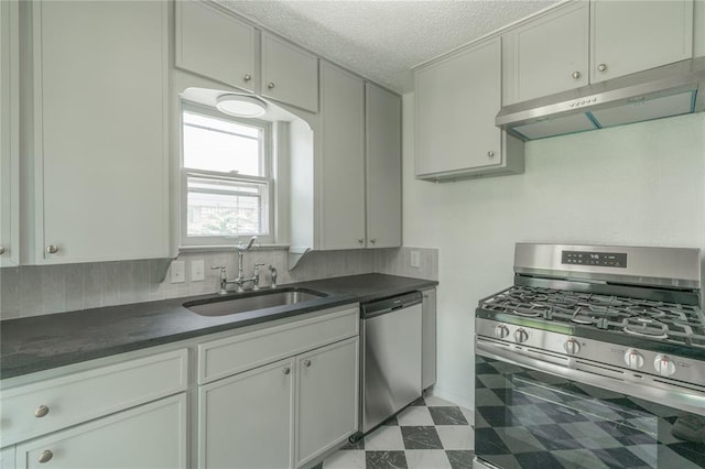 3125 NW 24th St, Oklahoma City, OK 73107 - kitchen with stainless steel appliances, a sink, under cabinet range hood, dark countertops, and a textured ceiling