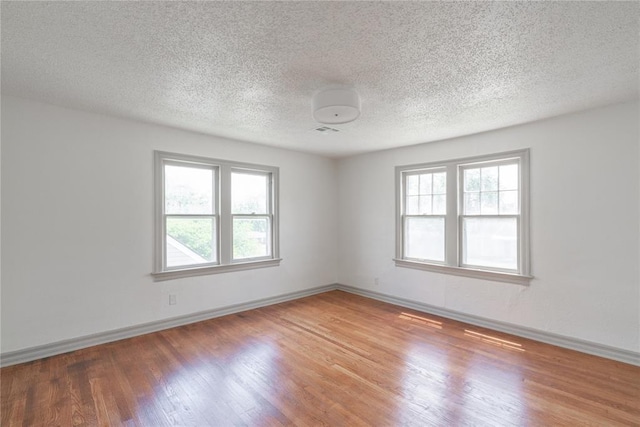 3125 NW 24th St, Oklahoma City, OK 73107 - empty room featuring healthy amount of natural light, wood finished floors, a textured ceiling, and baseboards
