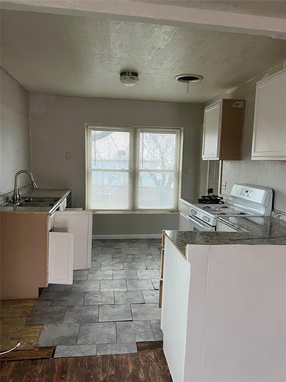 kitchen with white cabinetry, sink, kitchen peninsula, and white range with gas stovetop