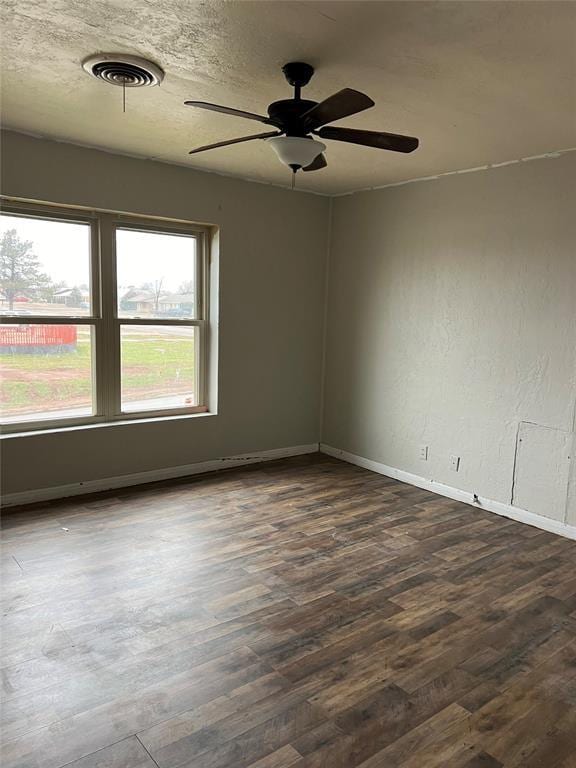 spare room featuring ceiling fan, dark wood-type flooring, and a textured ceiling