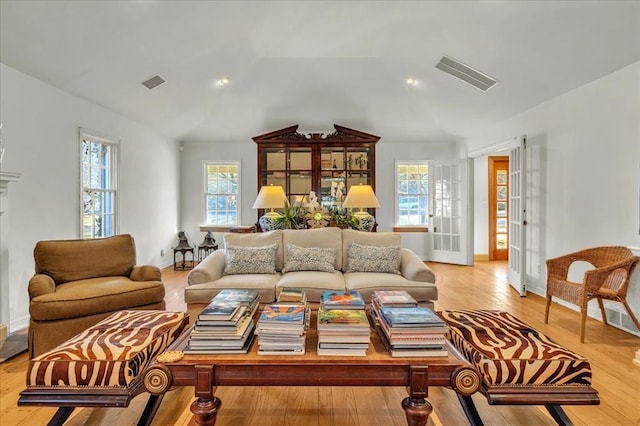 living area with lofted ceiling, visible vents, baseboards, and wood finished floors