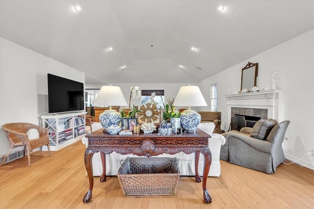 living room featuring vaulted ceiling, light wood-type flooring, a fireplace, and recessed lighting