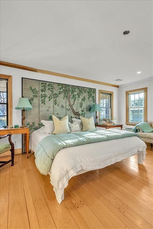 bedroom featuring wood-type flooring, visible vents, and crown molding