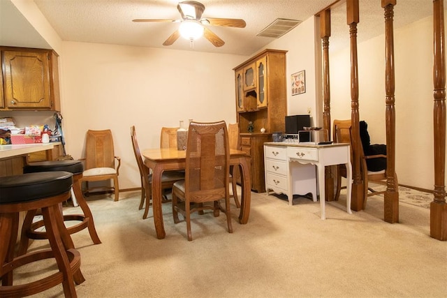 dining room with baseboards, visible vents, light colored carpet, ceiling fan, and a textured ceiling