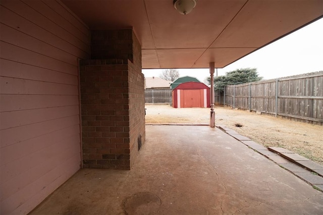 view of patio / terrace featuring an outbuilding, a fenced backyard, and a storage shed