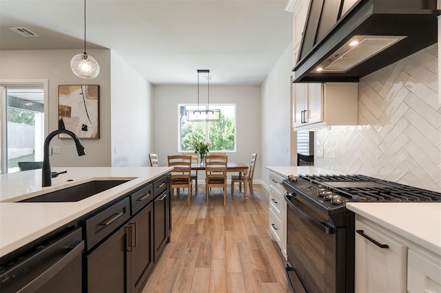 kitchen with sink, pendant lighting, white cabinets, and black appliances