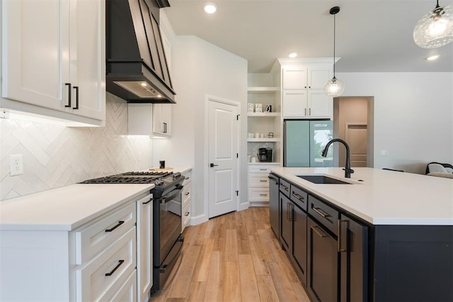 kitchen featuring sink, custom exhaust hood, gas stove, white cabinetry, and hanging light fixtures