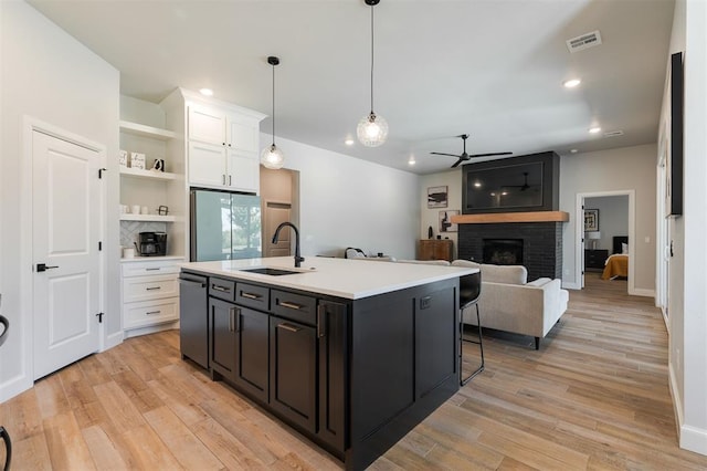 kitchen with white cabinetry, stainless steel dishwasher, a kitchen island with sink, and sink