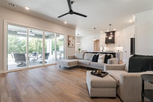 living room featuring sink, ceiling fan, and light wood-type flooring