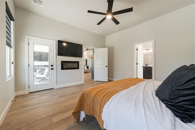 bedroom featuring connected bathroom, vaulted ceiling, light hardwood / wood-style flooring, ceiling fan, and access to exterior