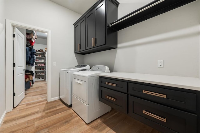 washroom featuring cabinets, washing machine and clothes dryer, and light hardwood / wood-style floors