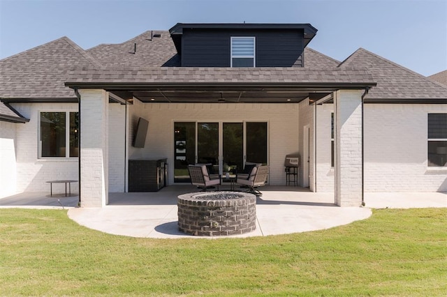 back of property with a patio, a lawn, and a fire pit