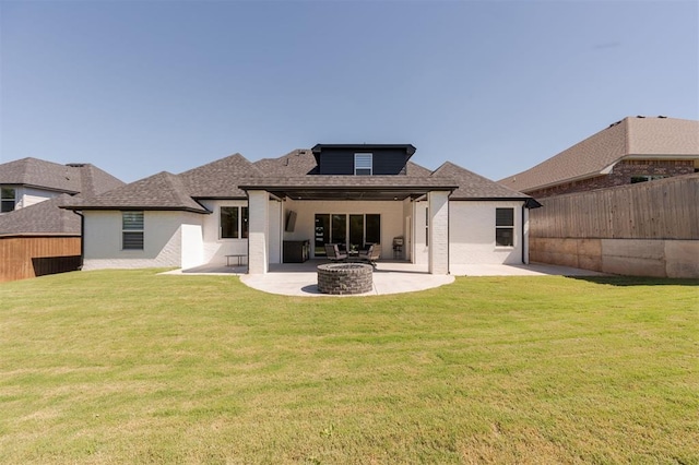 rear view of property featuring a yard, a patio area, and an outdoor fire pit