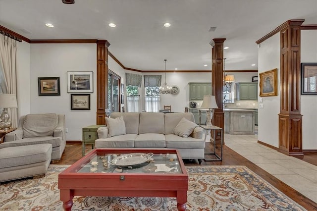 tiled living room with ornate columns, crown molding, and a chandelier