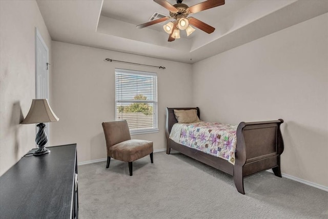 carpeted bedroom with a tray ceiling and ceiling fan