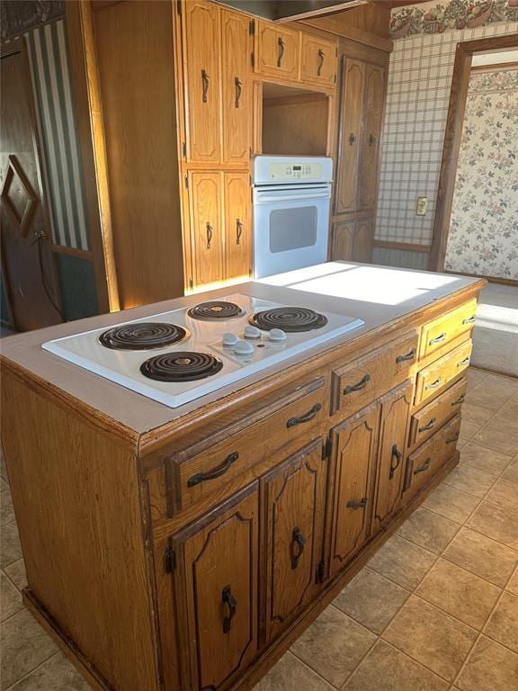 kitchen featuring cooktop, a kitchen island, and white oven