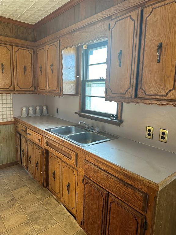 kitchen with light tile patterned flooring, sink, and wood walls