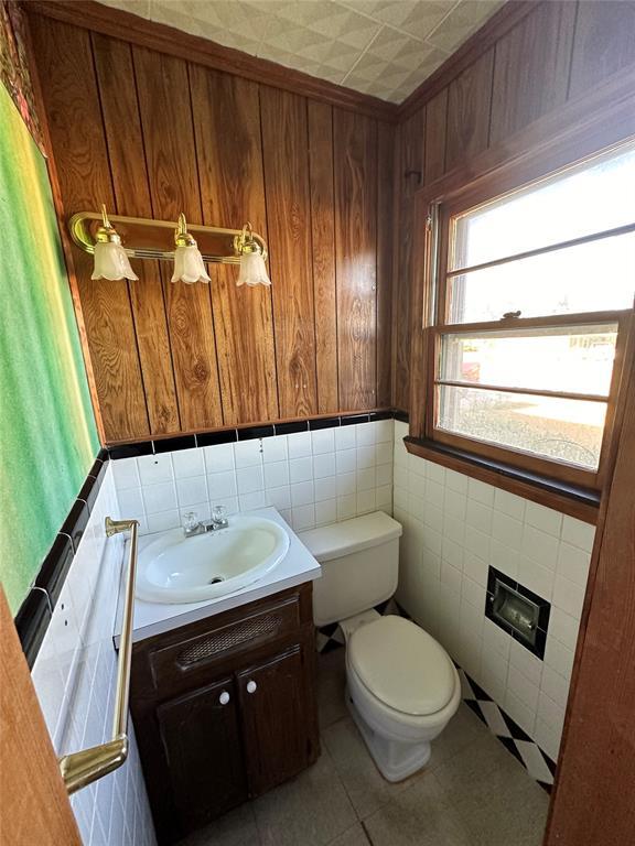 bathroom featuring vanity, tile patterned flooring, tile walls, and toilet