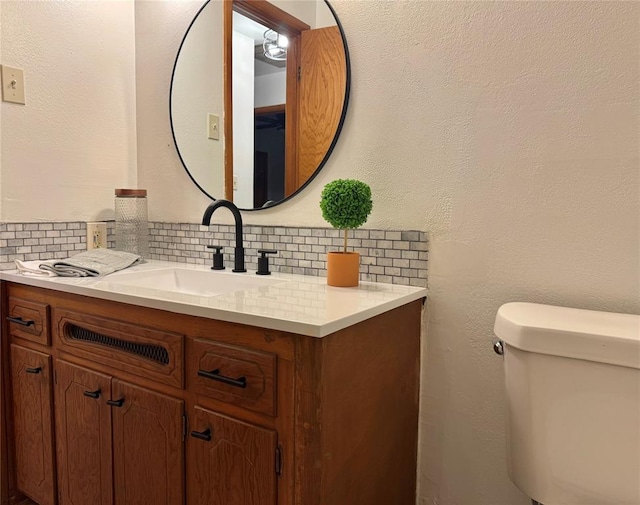 bathroom featuring toilet, vanity, and tasteful backsplash