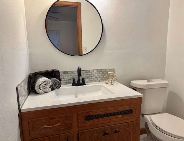 bathroom with toilet, vanity, and decorative backsplash