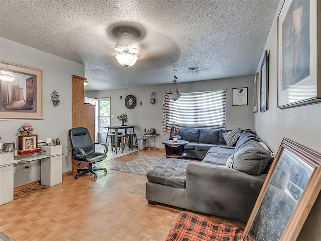 living room with ceiling fan, a textured ceiling, and light parquet flooring