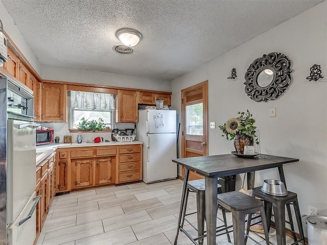 kitchen featuring a healthy amount of sunlight, white fridge, and a textured ceiling