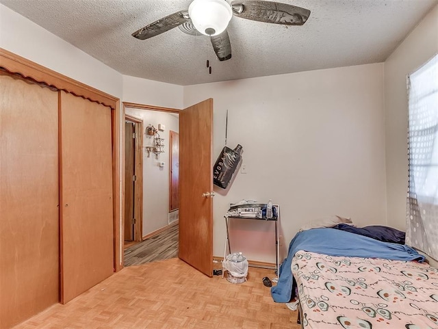 bedroom featuring ceiling fan, a textured ceiling, a closet, and light parquet flooring