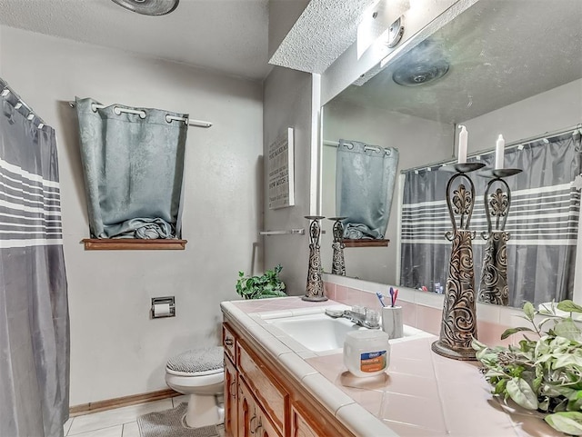 bathroom featuring tile patterned floors, toilet, vanity, and a textured ceiling