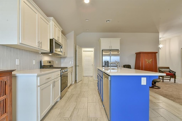 kitchen featuring an island with sink, sink, white cabinets, decorative backsplash, and stainless steel appliances