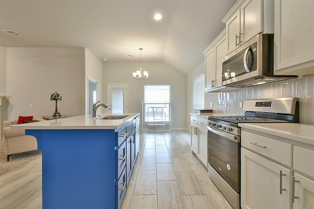 kitchen with blue cabinets, sink, white cabinetry, appliances with stainless steel finishes, and a kitchen island with sink