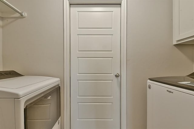 laundry area with independent washer and dryer and cabinets