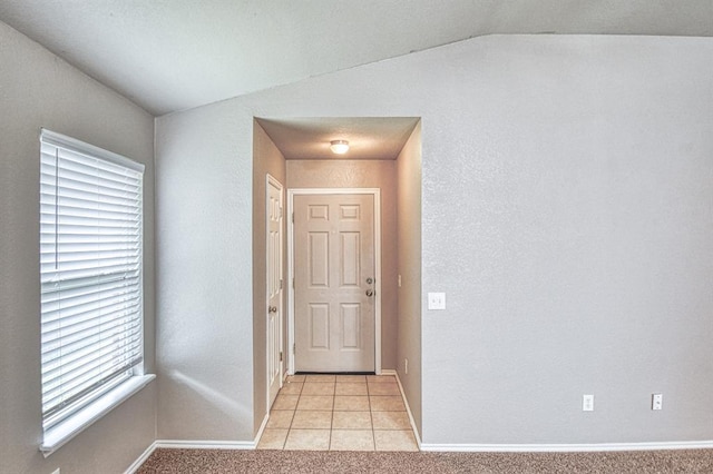 entrance foyer featuring vaulted ceiling, baseboards, and light tile patterned flooring