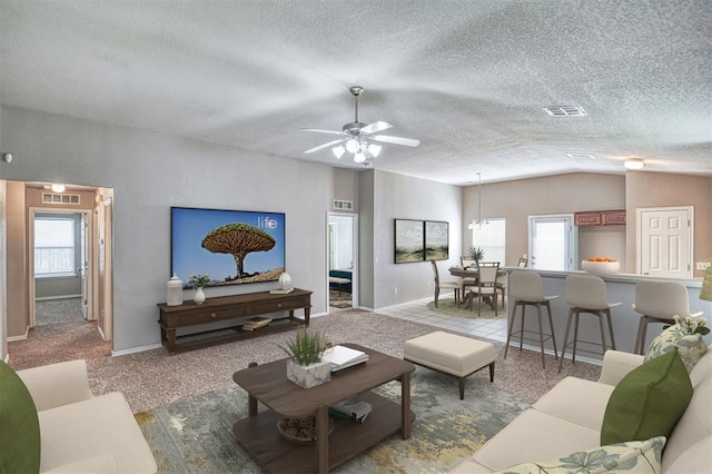 living area with healthy amount of natural light, vaulted ceiling, a textured ceiling, ceiling fan, and baseboards