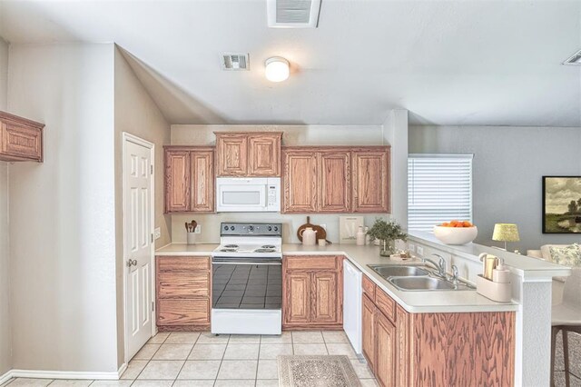 kitchen featuring white appliances, a sink, a peninsula, light countertops, and light tile patterned floors