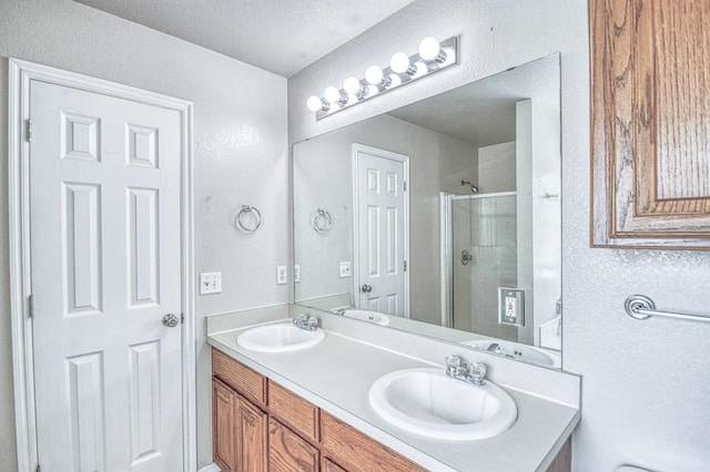 full bath with a stall shower, a textured wall, and double vanity