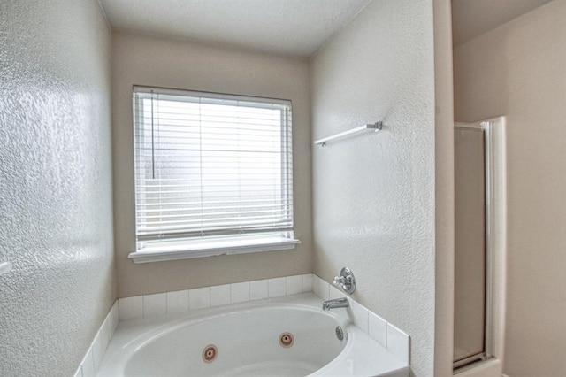 bathroom featuring healthy amount of natural light, a shower stall, a textured wall, and a whirlpool tub