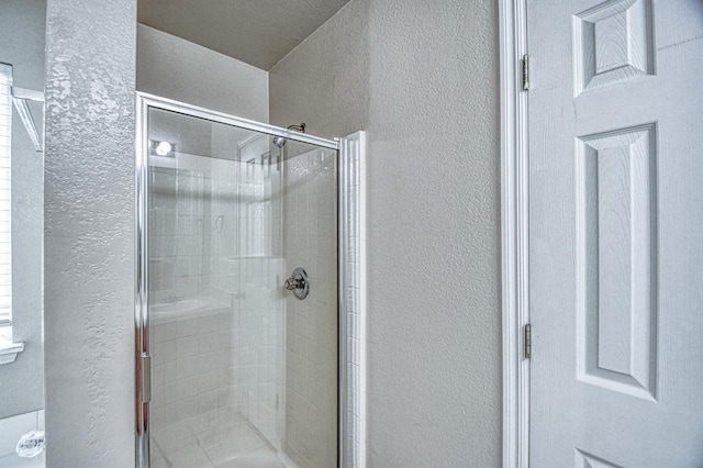 bathroom featuring a textured wall and a stall shower
