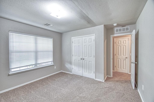 unfurnished bedroom with a textured ceiling, a closet, carpet floors, and baseboards