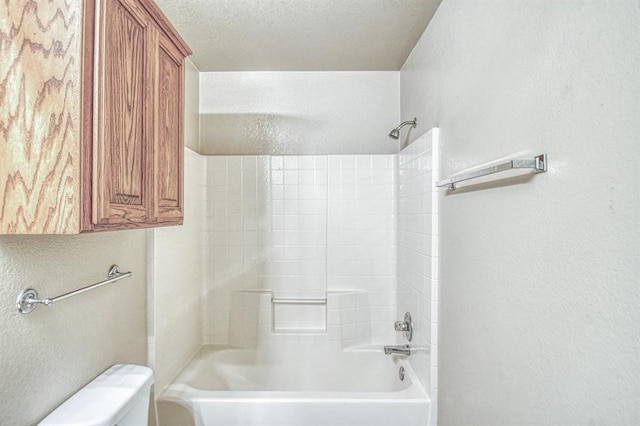 bathroom featuring a textured wall, toilet, and shower / bath combination