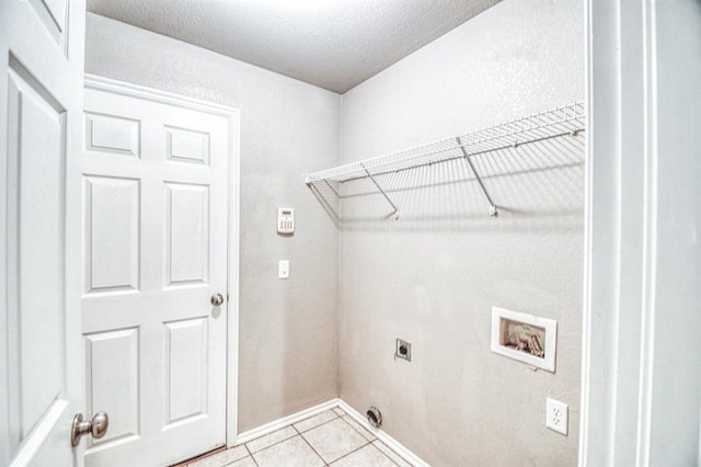 laundry area with electric dryer hookup, washer hookup, light tile patterned floors, baseboards, and a textured ceiling