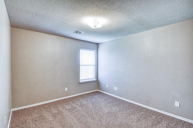 spare room featuring carpet floors, baseboards, a textured ceiling, and a textured wall