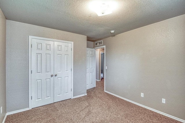 unfurnished bedroom featuring carpet, a closet, baseboards, and a textured ceiling