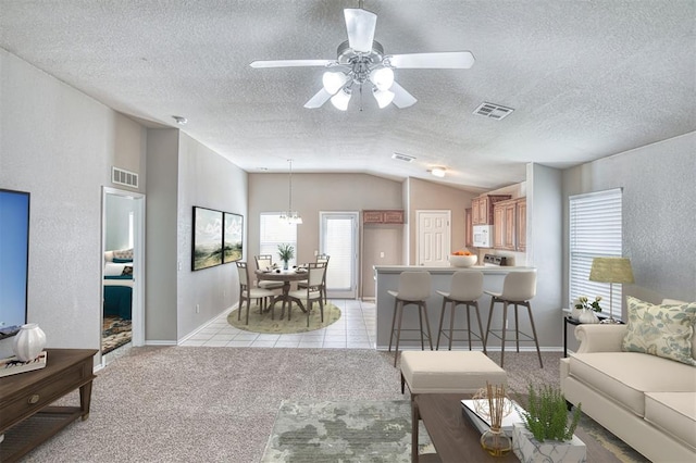 living area featuring vaulted ceiling, a textured ceiling, baseboards, a ceiling fan, and light carpet