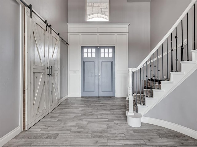 entrance foyer featuring a towering ceiling, a barn door, and light wood-type flooring