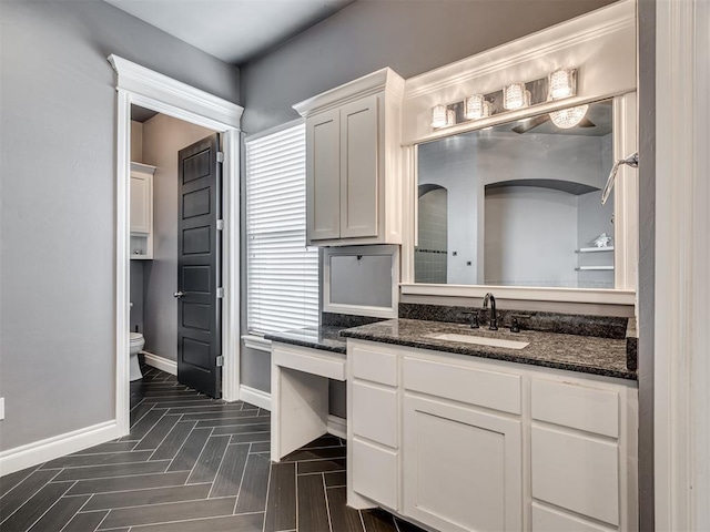 bathroom with parquet flooring, vanity, and toilet