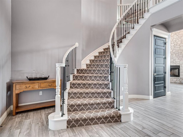 stairs with a towering ceiling, a fireplace, and hardwood / wood-style floors