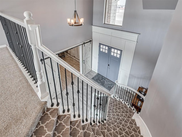 stairway with carpet floors, a chandelier, and a high ceiling