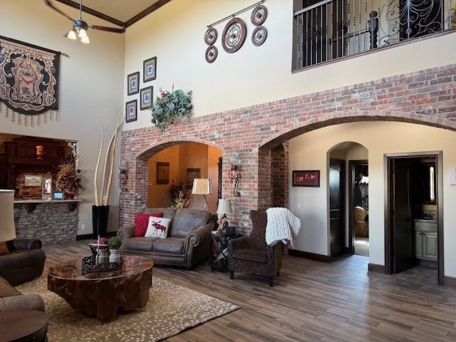 living room with a towering ceiling, ornamental molding, brick wall, and hardwood / wood-style flooring